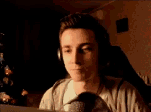 a man wearing headphones is smiling while looking at a computer screen .