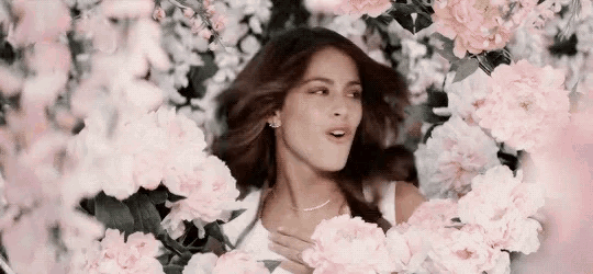 a woman is surrounded by pink and white flowers .