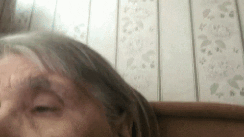 a close up of a woman 's face with her eyes closed in front of a wall with flowers on it