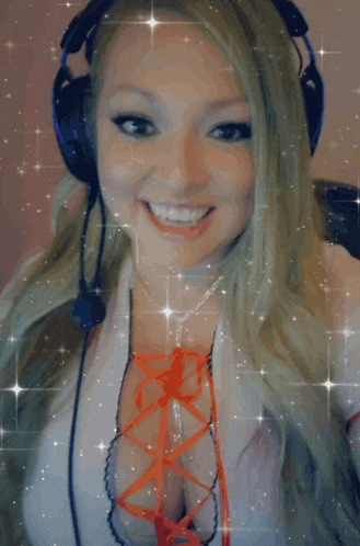 a blonde woman wearing headphones and a necklace smiles