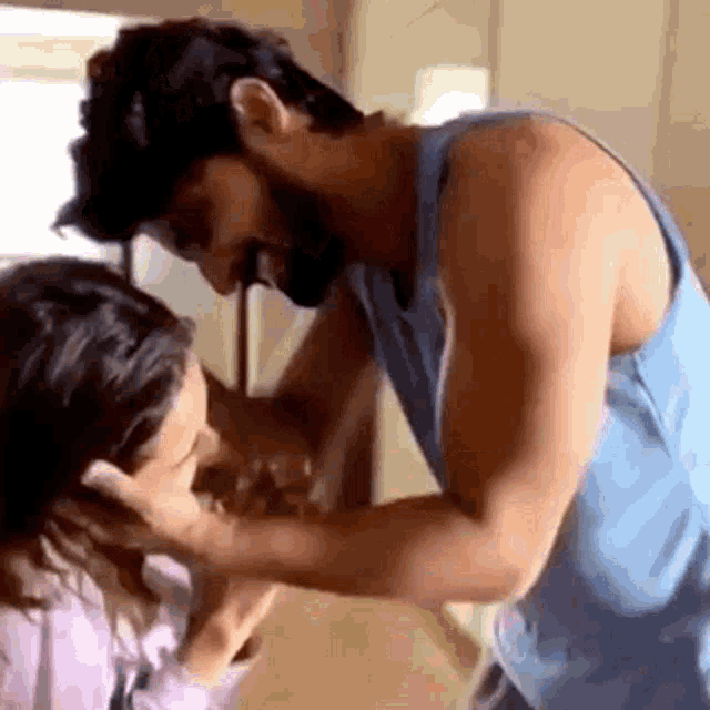 a man is touching a woman 's face while standing next to her in a room .