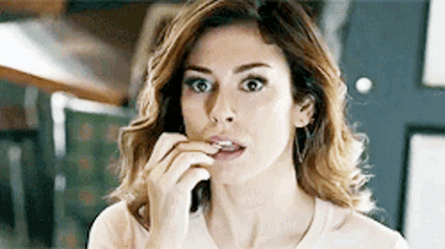 a woman is biting her nails while looking at herself in the mirror .