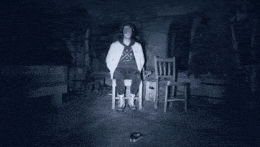 a man is sitting in a chair in a dark room with headphones on his head .