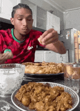 a man wearing a red puma shirt is eating some food