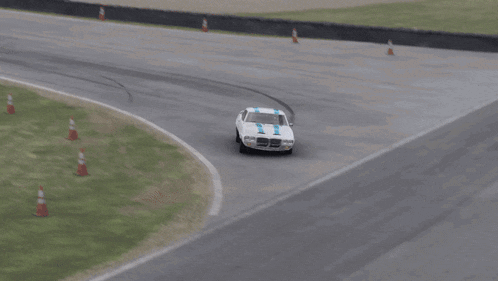 a white car with blue stripes on the side is driving on a road