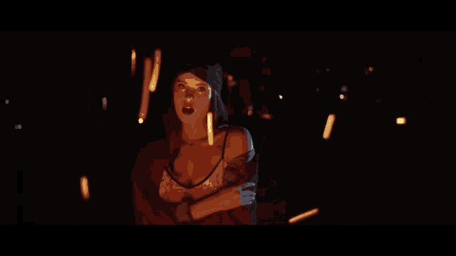 a woman is standing in a dark room holding candles