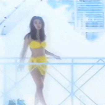 a woman in a yellow bikini is standing behind a railing