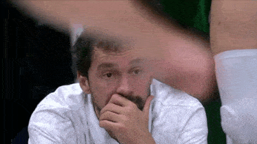 a man with a beard is covering his mouth with his hands
