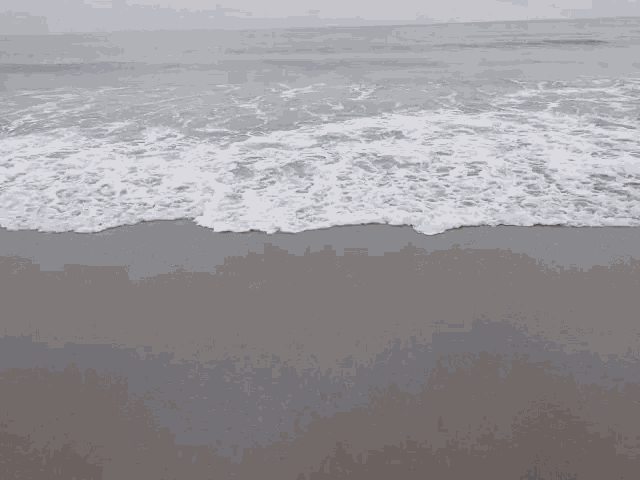 waves crashing on a sandy beach with foam on the sand