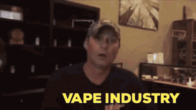 a man in a hat is standing in front of a wall that says vape industry