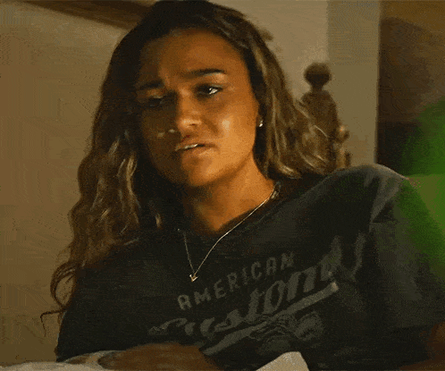 a close up of a woman wearing a t-shirt with a picture on the wall in the background .