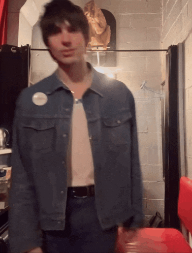 a man in a denim jacket has a badge on his chest