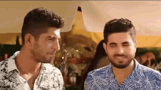 two men are standing next to each other and talking .