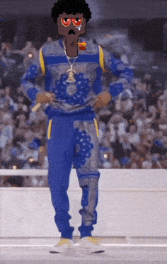 a man wearing a blue sweater and blue pants stands in front of a crowd with a lollipop in his mouth