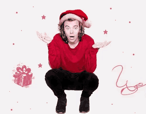 harry styles is wearing a santa hat and kneeling down with his hands outstretched .