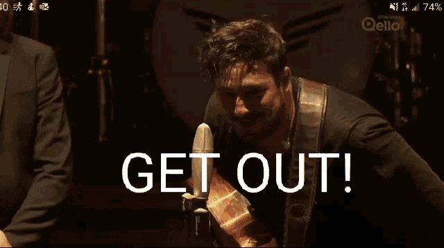 a man is playing a guitar in front of a microphone and the words get out are displayed