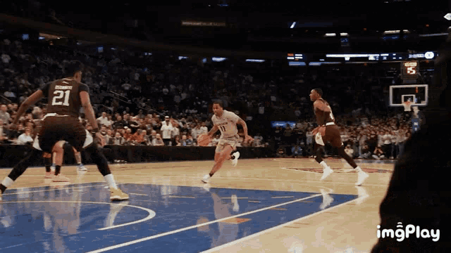 a basketball player with the number 21 on his jersey dribbles the ball