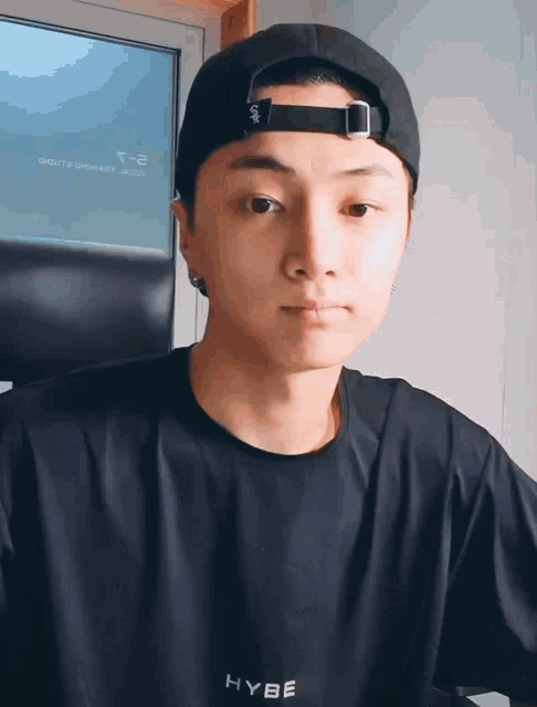 a young man wearing a black shirt that says hybe on it