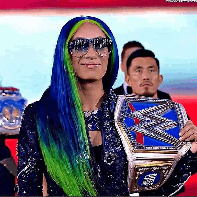 a woman with blue and green hair is holding a world heavyweight wrestling championship belt