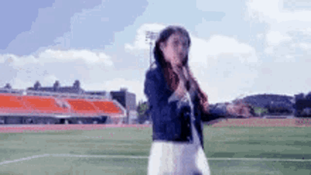a woman is singing into a microphone while standing on a field .