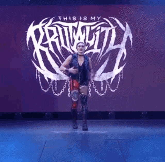 a wrestler is standing in front of a large screen that says this is my rivalry