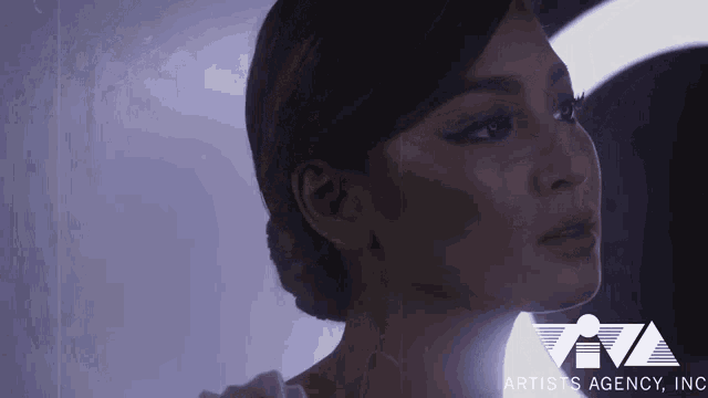 a close up of a woman 's face with the artists agency inc. logo in the background