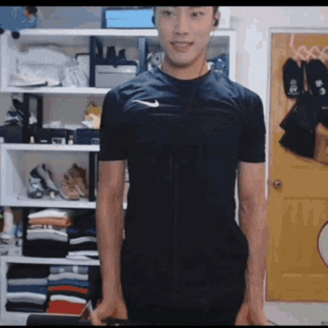 a man wearing a nike shirt is standing in front of a closet