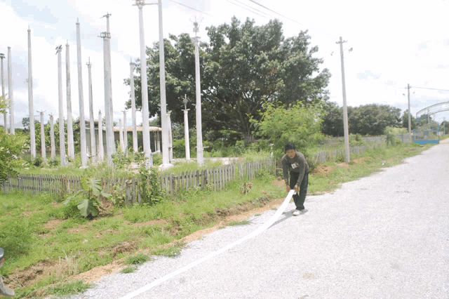 a man is standing on the side of a road holding a piece of white paper