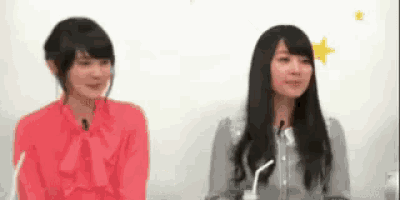 two women are sitting next to each other in front of microphones .