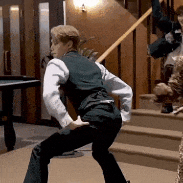 a man in a suit is standing on a set of stairs and dancing .
