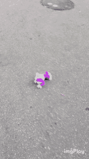 a purple and white stuffed animal is laying on the ground with a yellow object nearby