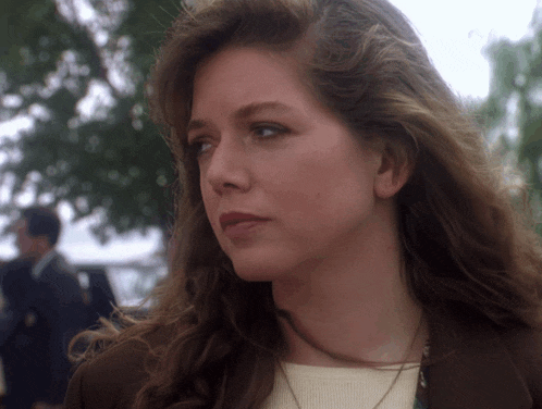 a close up of a woman 's face with a man in a suit in the background