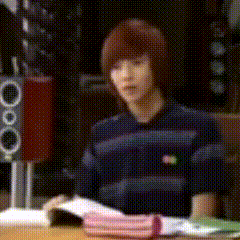 a person is sitting at a table with a book and a pink pencil case