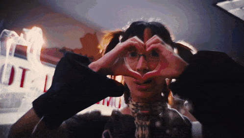 a person making a heart shape with their hands in front of a sign that says out