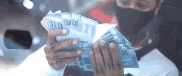a man wearing a mask is holding a stack of money in his hands