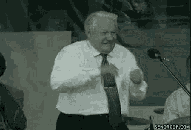 a man in a tie is dancing in front of a microphone .