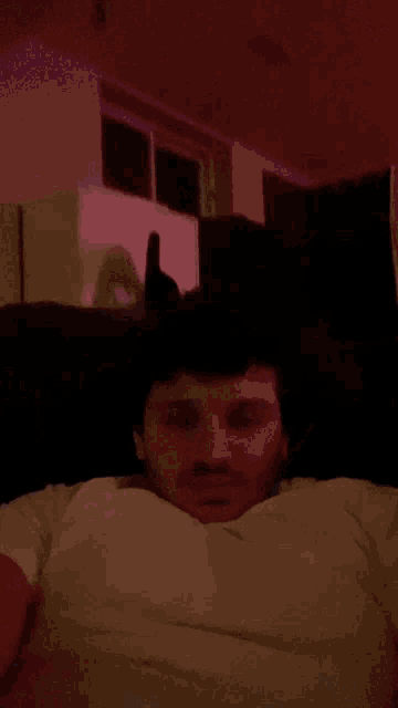 a man in a white shirt is laying on a couch in a dark room