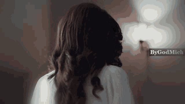 a woman 's back is shown in a blurry photo with the words bygodmich visible in the corner