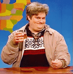 a man in a sweater and jacket holds a glass of whiskey