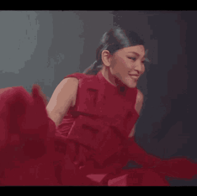 a woman in a red dress and red gloves is smiling and clapping .