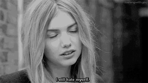 a black and white photo of a woman with the words `` i still hate myself '' written on her face .
