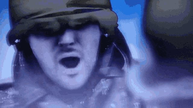 a close up of a man wearing a helmet with his mouth wide open