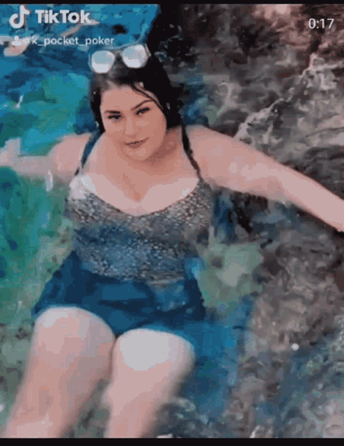 a woman in a bathing suit is swimming in a pool with a tiktok watermark at the bottom
