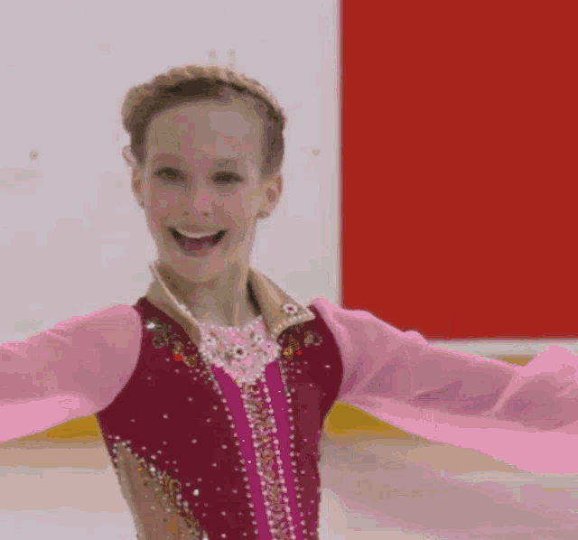 a young girl in a pink and gold outfit smiles