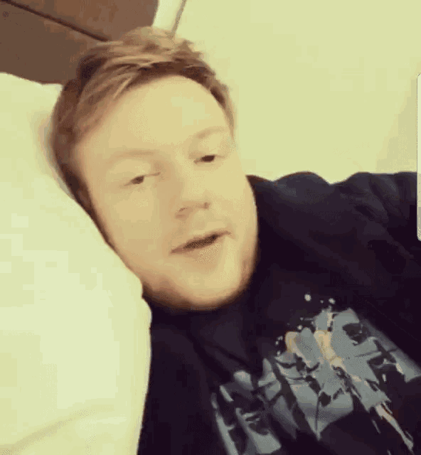 a man wearing a star wars shirt is laying in bed