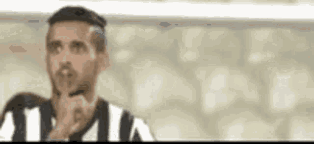 a man in a striped shirt is holding his finger to his mouth and thinking .