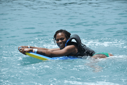 a woman in a life jacket is floating on a boogie board in the water