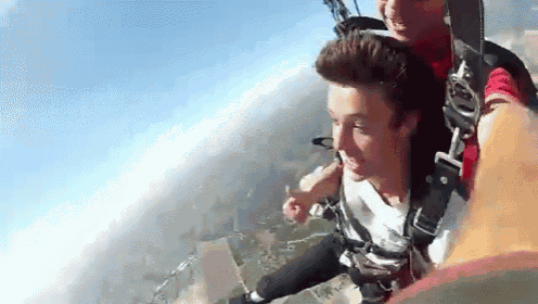 a man and a boy are flying through the air with a parachute on .