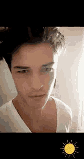 a close up of a young man 's face with a sun in the background .