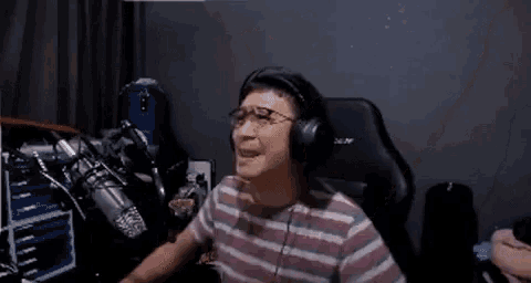a man wearing headphones is sitting in a chair in front of a microphone in a room .